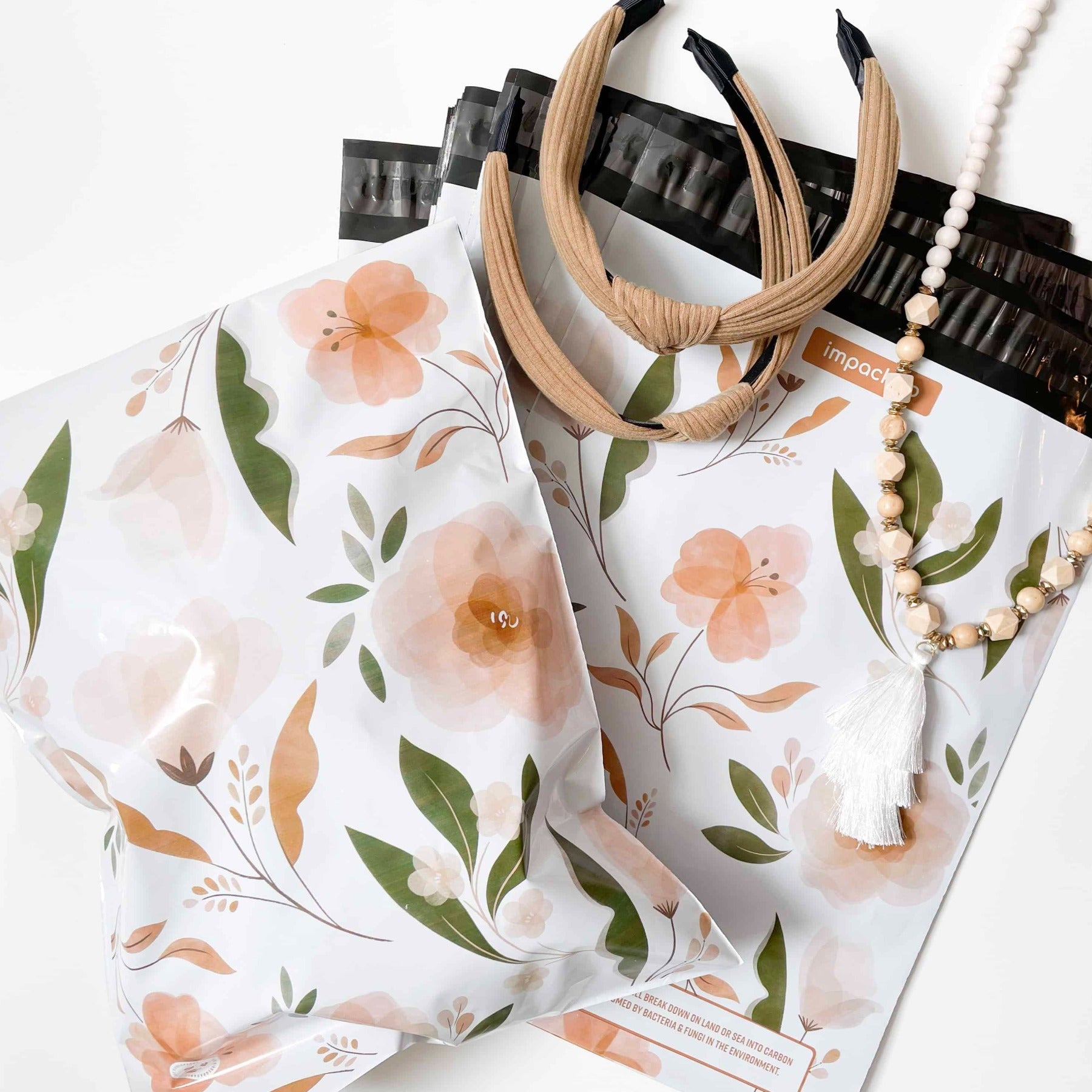 Description: A recyclable bag with a matte effect, containing Camelia Bloom Biodegradable Mailers 14.5" x 19" necklace and earrings from impack.co.