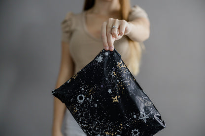 A woman is holding up a recyclable Midnight Galaxy Mailers 10" x 13" pouch with stars on it from impack.co.