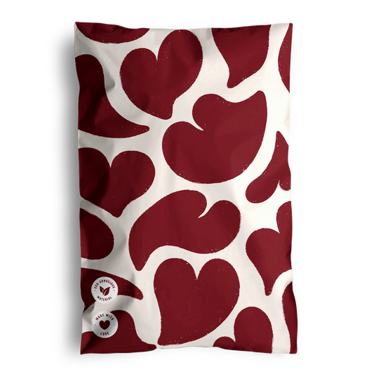 A fabric with impack.co's Red Hearts Biodegradable Mailers 6" x 9" on a white background, folded and placed against a dark backdrop.