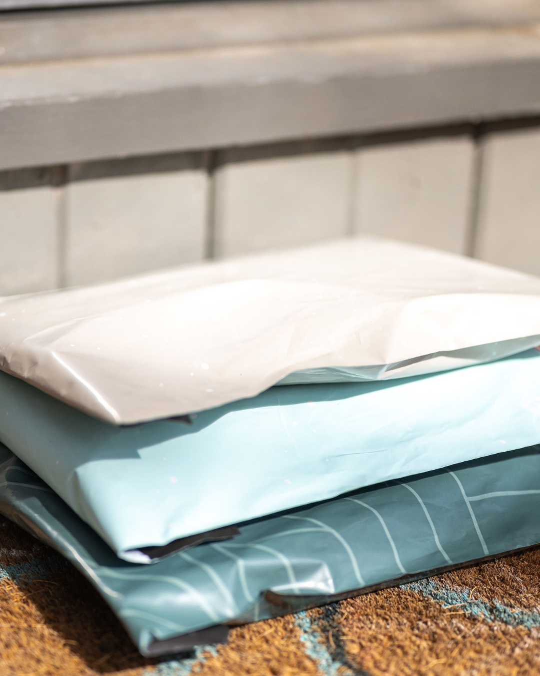 Three plastic packages are stacked on a doormat in front of a door.