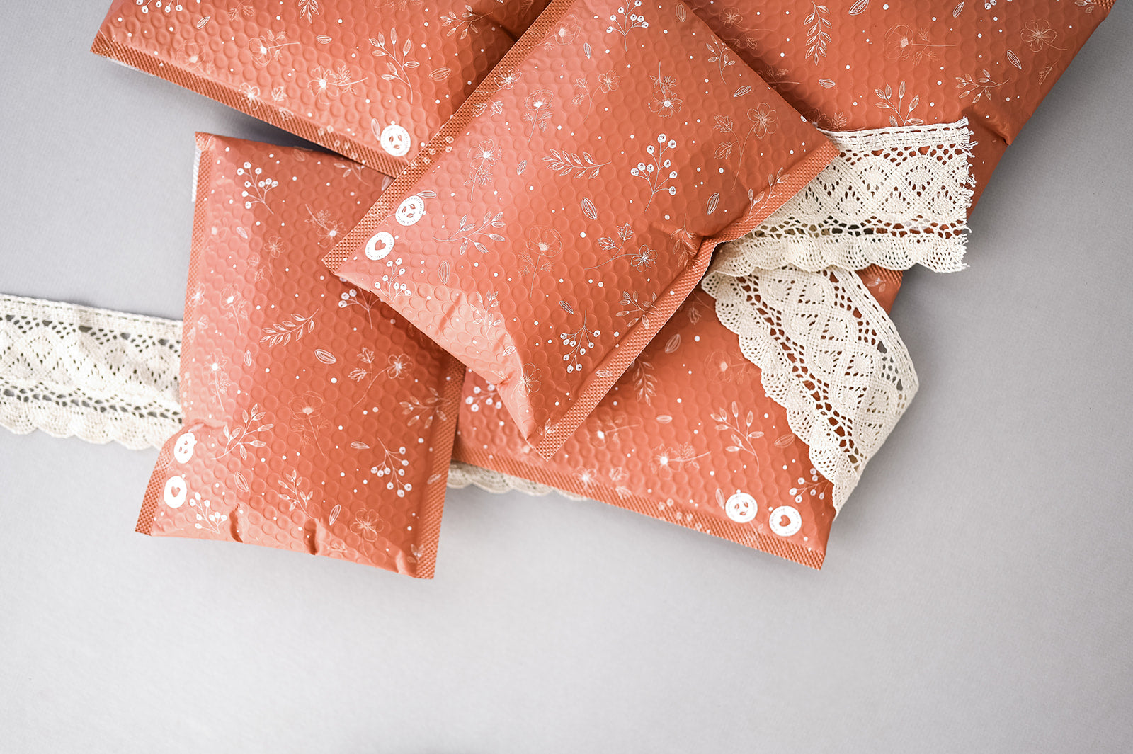 A bunch of Rosy Brown Biodegradable Bubble Mailers 6" x 9" with lace on them, perfect as mailers or packaging from impack.co.