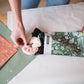 A woman is putting an Emerald Evergreen Biodegradable Mailers 6" x 9" from impack.co into a bag.
