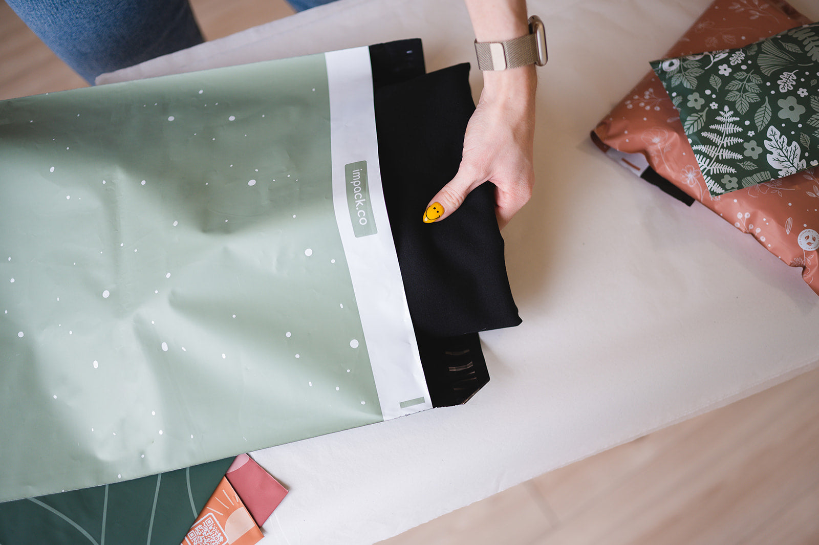 A woman is opening up a Starry Lily Pad Biodegradable Mailers 14.5" x 19" bag of fabric on a table, made by impack.co.