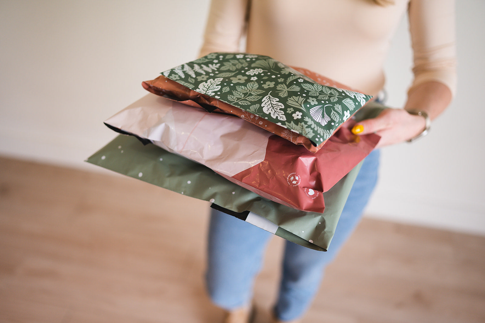 A woman is holding a bunch of impack.co's Emerald Evergreen Biodegradable Mailers 6" x 9".