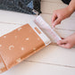 A person is putting a Celestial Tan Biodegradable Bubble Mailer 8.5" x 12" from impack.co into a wooden floor.
