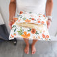 A woman is holding a bag of orange florals in Gardenlumina Padded Paper Mailers 10" x 13" from impack.co.