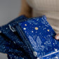 A woman holding a recyclable Midnight Indigo Mailers 10" x 13" from impack.co with stars on it.