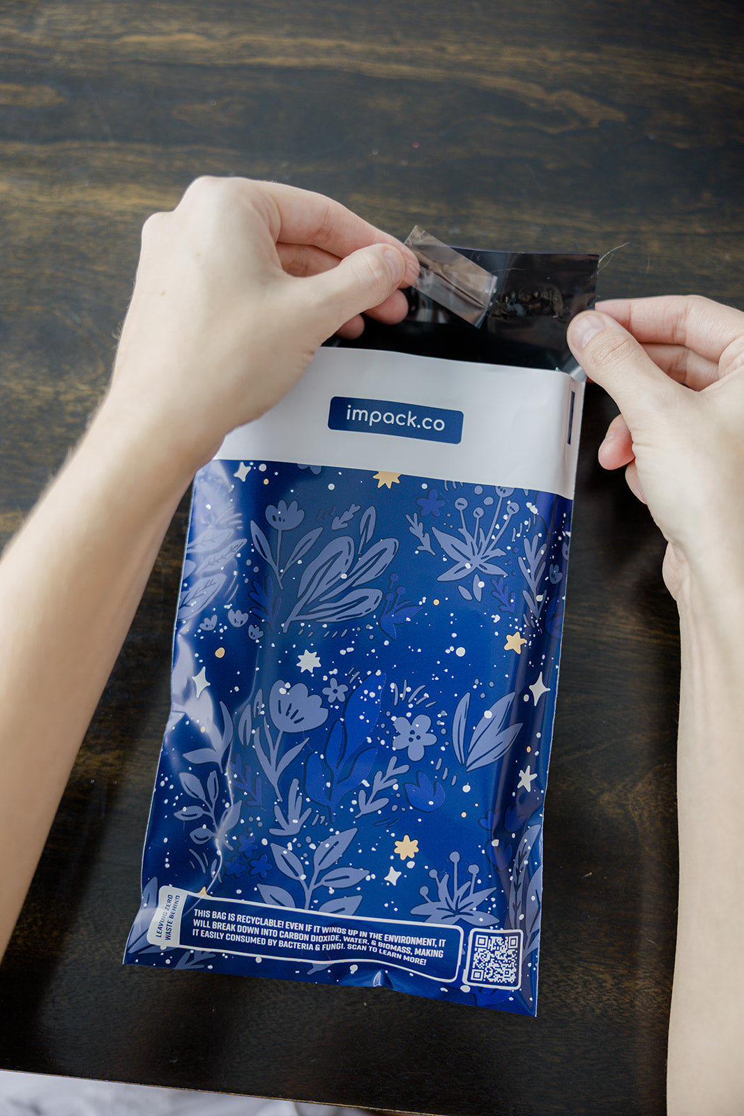 A person is holding a Midnight Indigo Mailers 6" x 9" recyclable bag from impack.co.