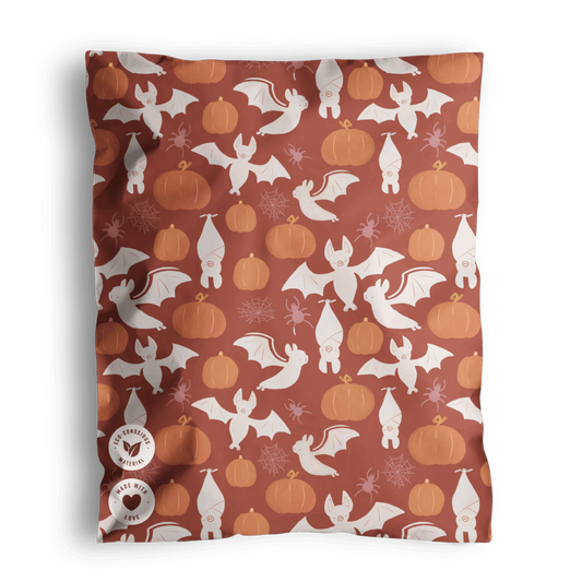 Halloween-themed biodegradable fabric featuring ghosts, pumpkins, and bats on a brown background from impack.co.
