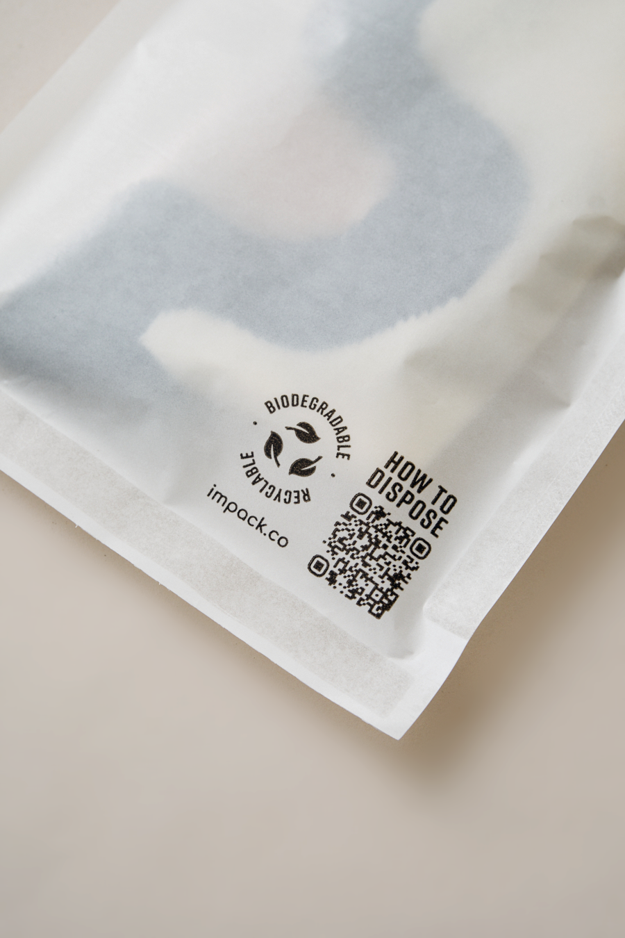 Close-up of a biodegradable packaging with a QR code and text instructions for disposal. The package features a logo and the website "impack.co" for the Glassine Bags 5.6" x 8.6" by impack.co.