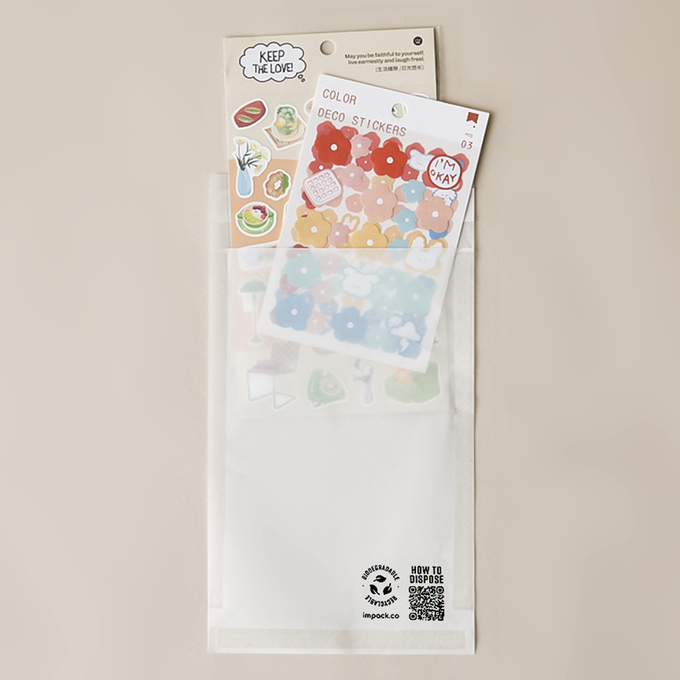 Two packs of decorative stickers featuring fruits, vegetables, and flowers on top of an impack.co Glassine Bags 5.6" x 8.6" with a 'How to Dispose' QR code at the bottom.