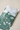 A green floral-patterned plastic mailing bag partially open revealing a Glassine Bag 9.6" x 12.6" by impack.co inside.