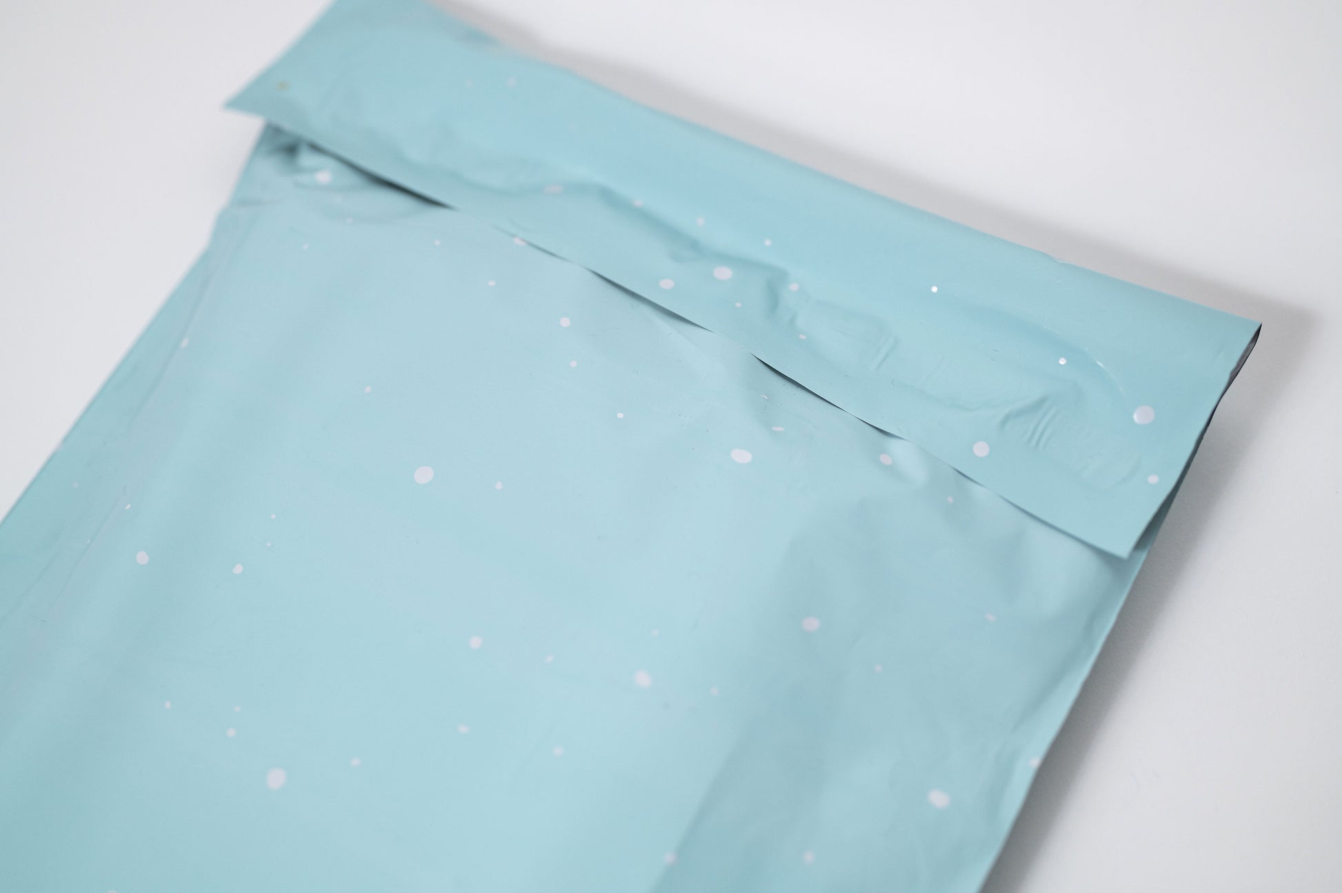 A Starry Baby Blue Biodegradable Mailer 10" x 13" with white snowflakes on it, made from recyclable materials, by impack.co.