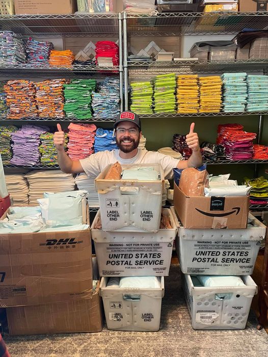 A man giving thumbs up in front of environmentally friendly packaging for diapers.