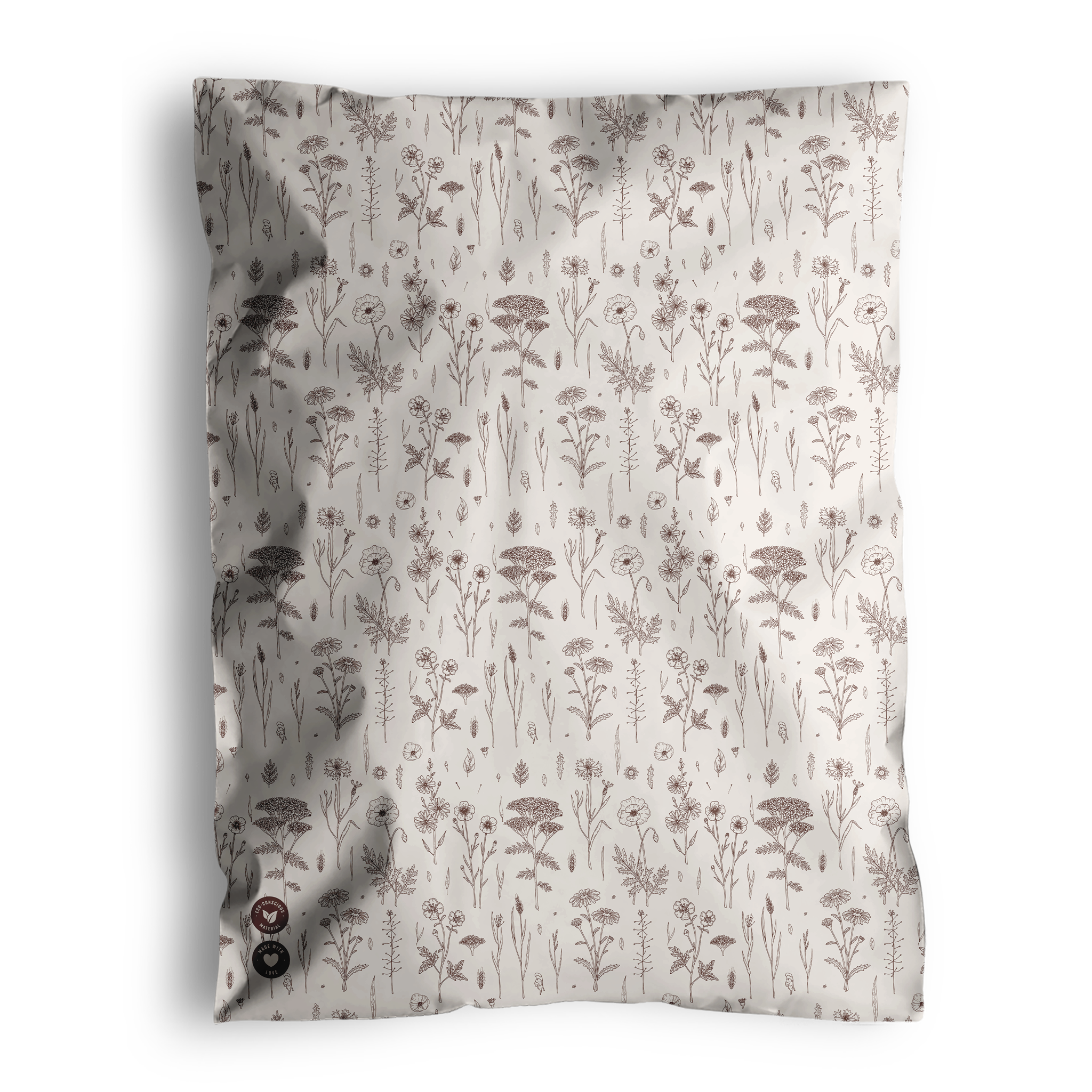 A cream-colored blanket featuring an elegant pattern of brown floral and botanical designs is delivered in Wildflower Biodegradable Mailers by impack.co, combining style with eco-friendly packaging.