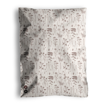 A cream-colored blanket featuring an elegant pattern of brown floral and botanical designs is delivered in Wildflower Biodegradable Mailers by impack.co, combining style with eco-friendly packaging.