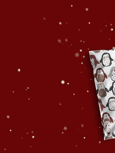 Two decorative pillows with festive patterns on a maroon background with white specks resembling snow.