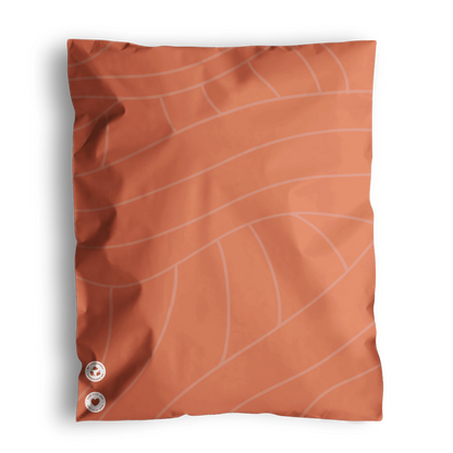 Orange cushion with a leaf vein pattern and two round metallic buttons on a dark background, presented in impack.co Natural Cedar Leaf Biodegradable Mailers 14.5" x 19".