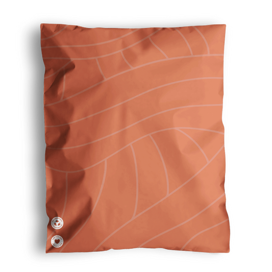 Orange cushion with a leaf vein pattern and two round metallic buttons on a dark background, presented in impack.co Natural Cedar Leaf Biodegradable Mailers 14.5" x 19".