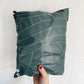 A person holding up a recyclable Olive Leaf Biodegradable Mailers 10" x 13" pillow by impack.co.