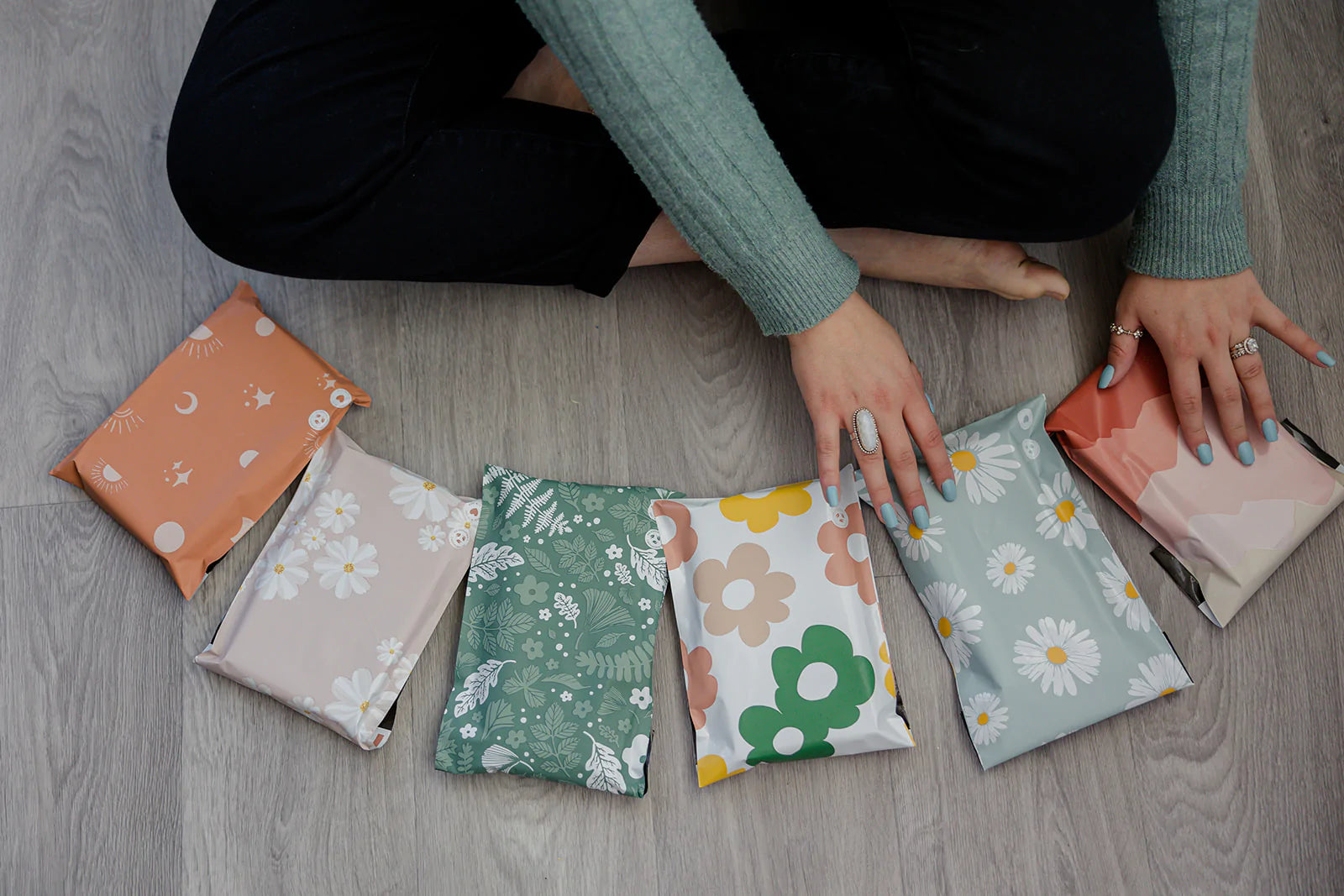 A woman is sitting on a wooden floor surrounded by eco-friendly packaging pouches.