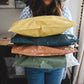 A woman holding a stack of pillows in her Mustard Leaf Biodegradable Mailers 14.5" x 19" office by impack.co.