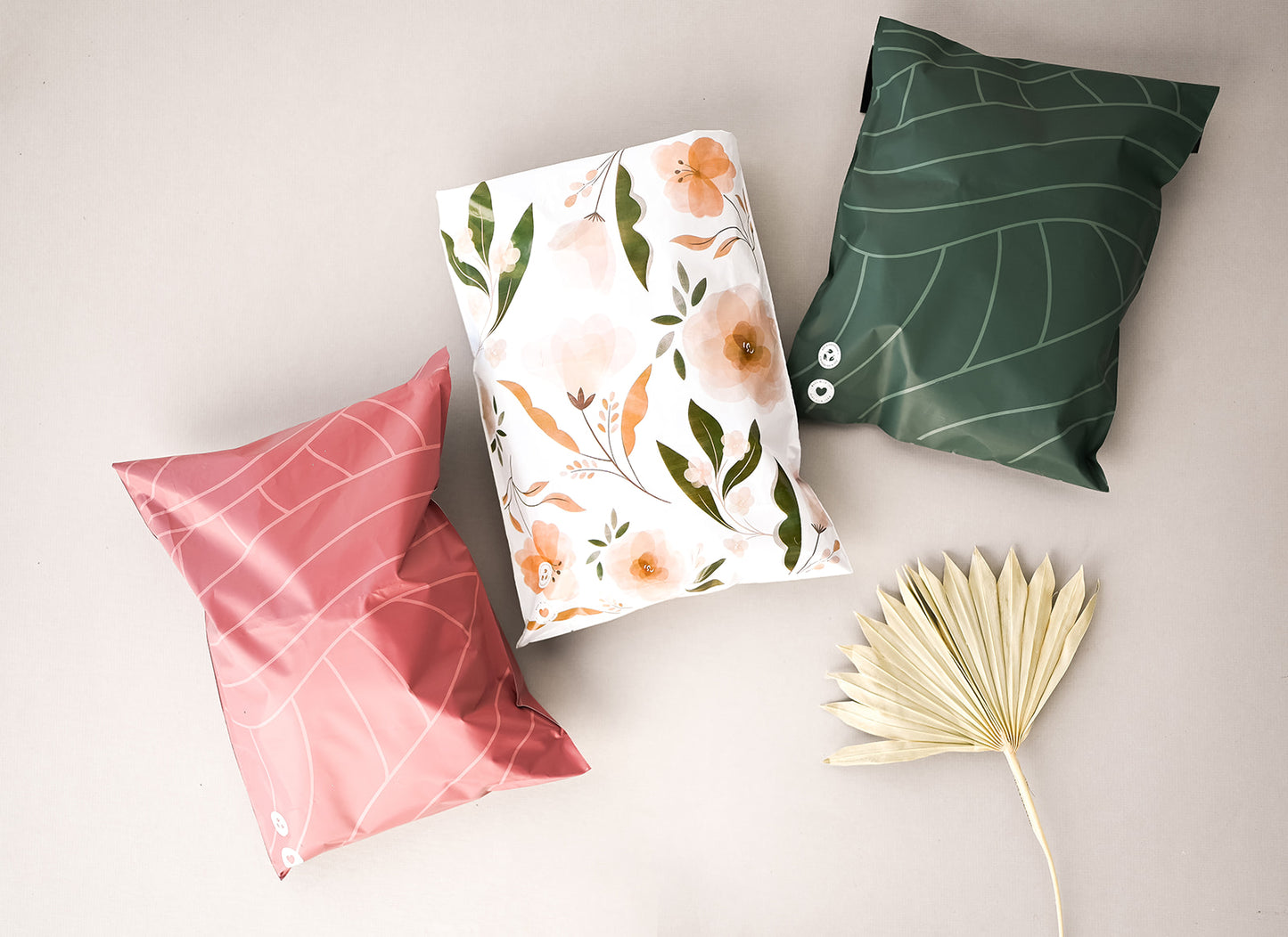 Three Olive Leaf Biodegradable Mailers 14.5" x 19" with flowers on them and a leaf next to them from impack.co.