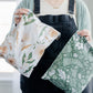 A woman is holding up two Biodegradable Mailer 10" x 13"" bags with floral prints on them from impack.co.