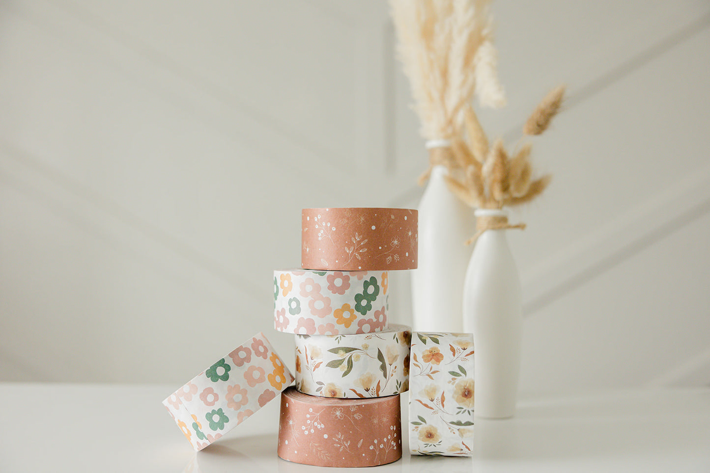 A stack of Packing Tape - Daisy Multi by impack.co on a white table.