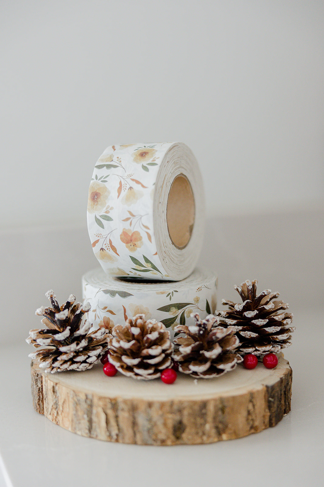 A roll of Packing Tape - Camelia Bloom with pine cones on top.