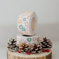A roll of Daisy Multi packing tape with pine cones on top.