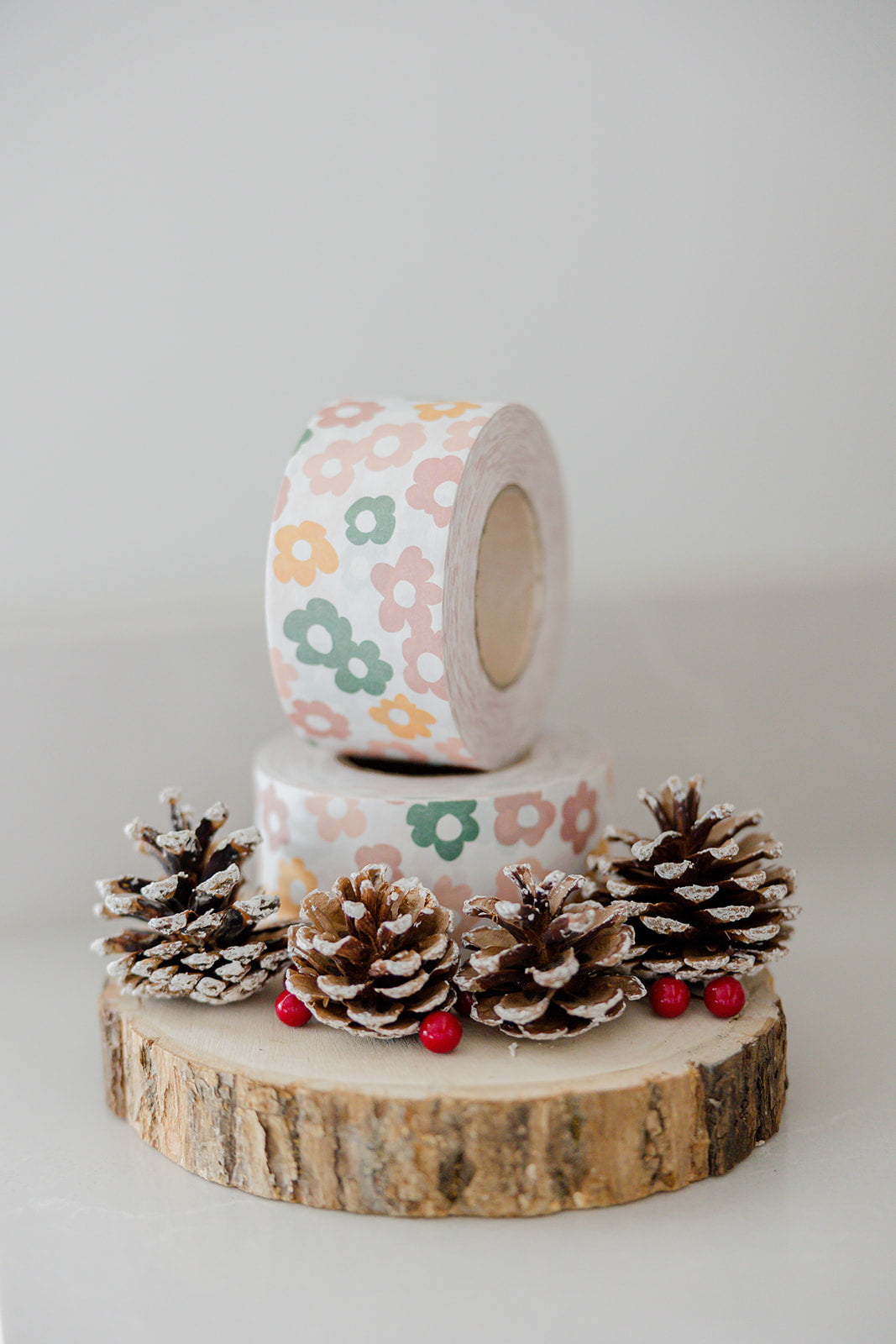A roll of Daisy Multi packing tape with pine cones on top.