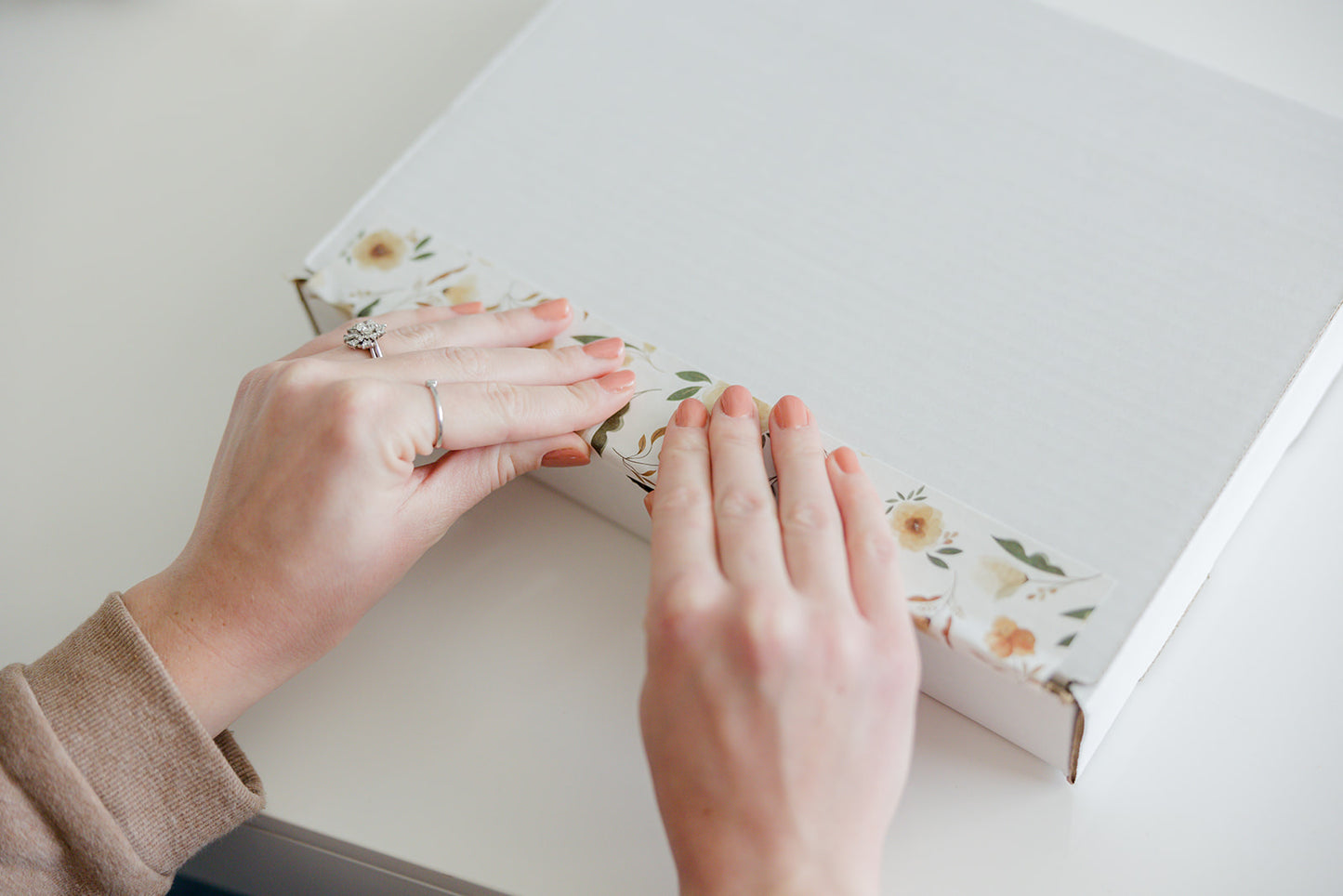 A woman is opening a white box with flowers and packing tape - Camelia Bloom - Canada Stock, from impack.co on it.