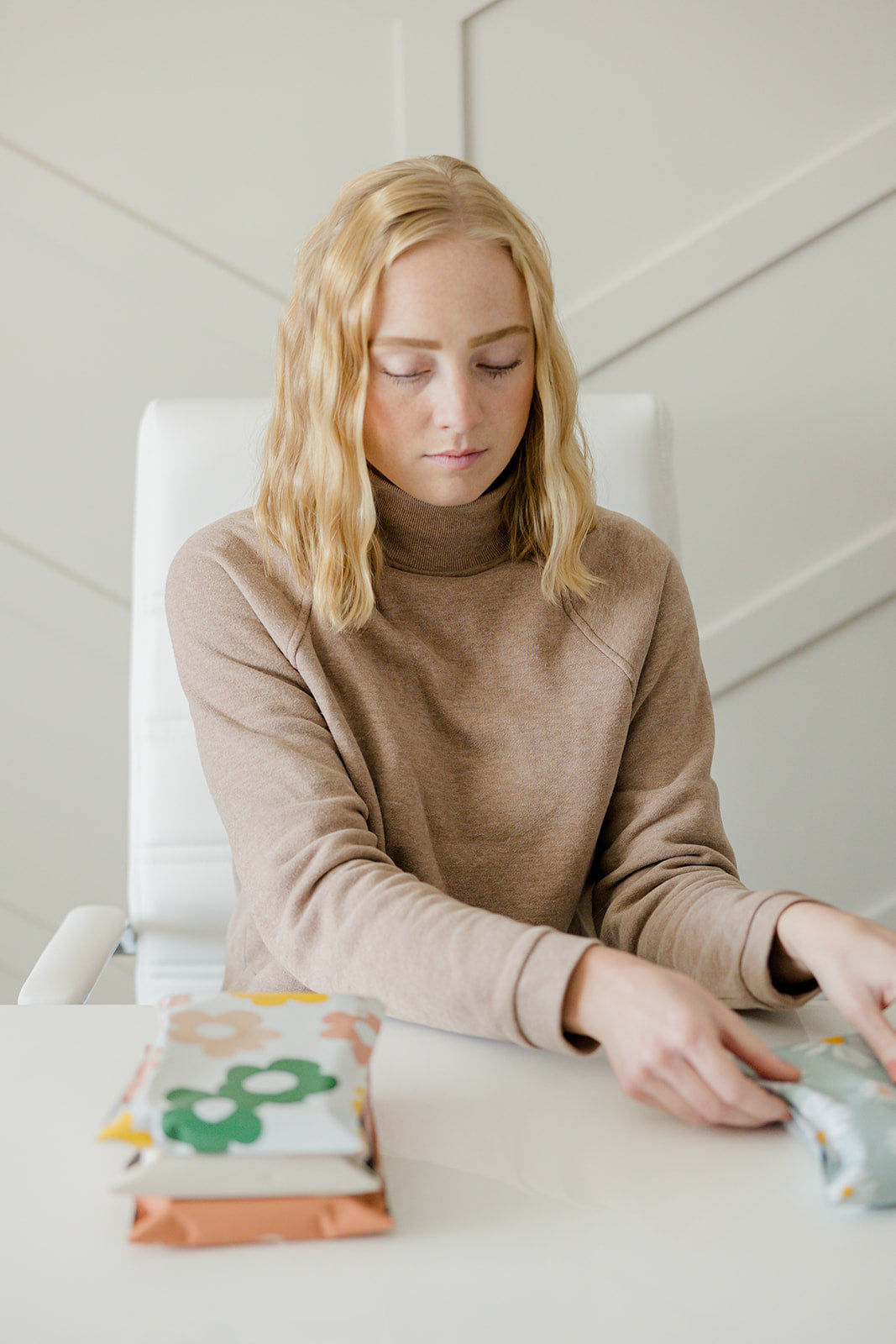 A woman sitting at a table with Daisy Multicolor Biodegradable Mailers 10" x 13" from impack.co.
