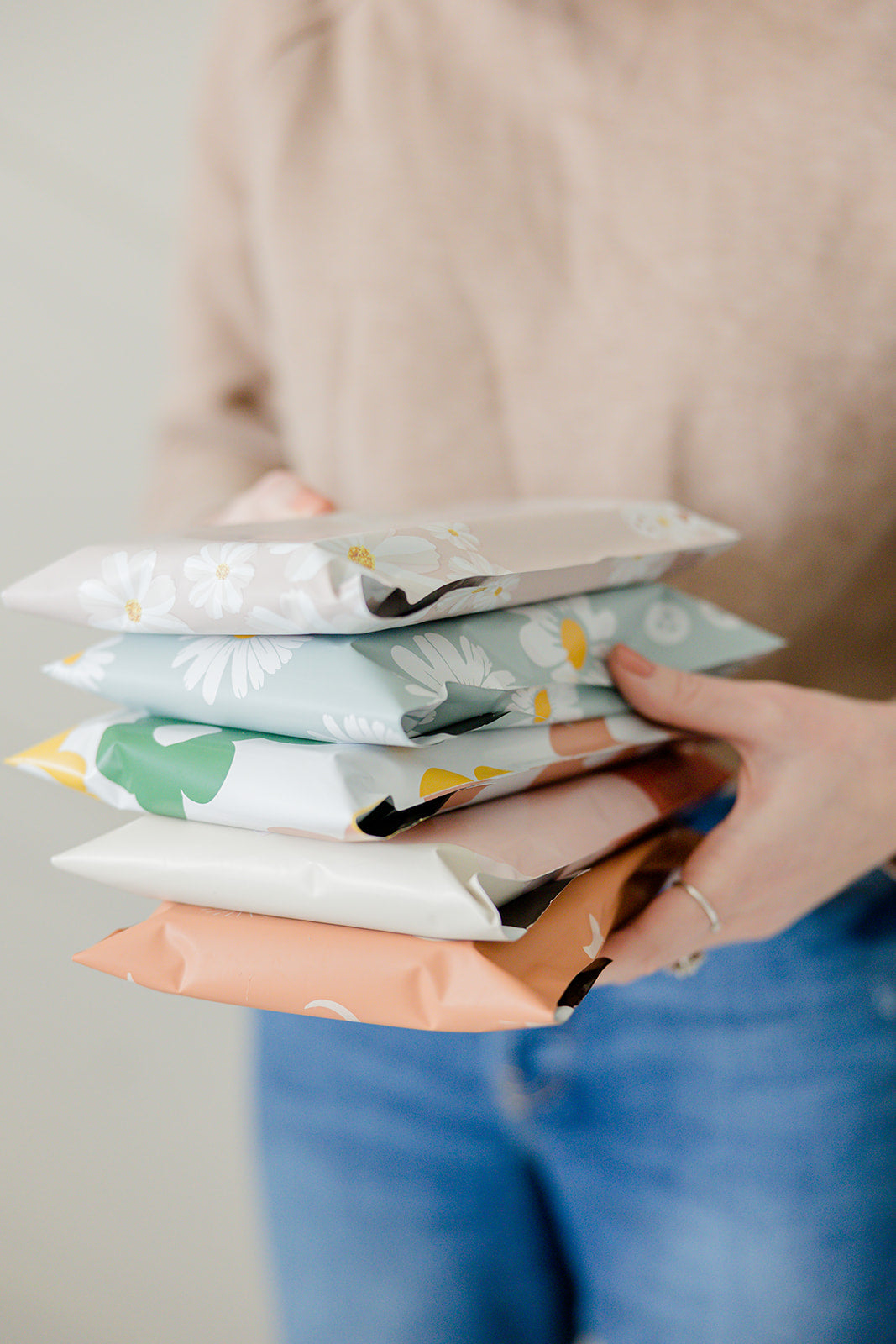 A woman holding a stack of impack.co Biodegradable Mailer bags 10" x 13".
